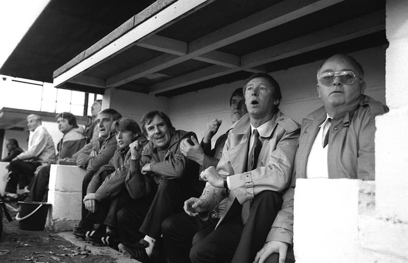 November 1986 Ferguson and coaching staff watch Man Utd crash to a 2-0 defeat at Oxford United - Fergie almost lost his job because of this result
