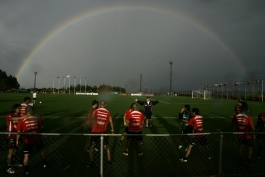 A rainbow forms in the sodden skies behind Chile coach Nelson Acosta and his players